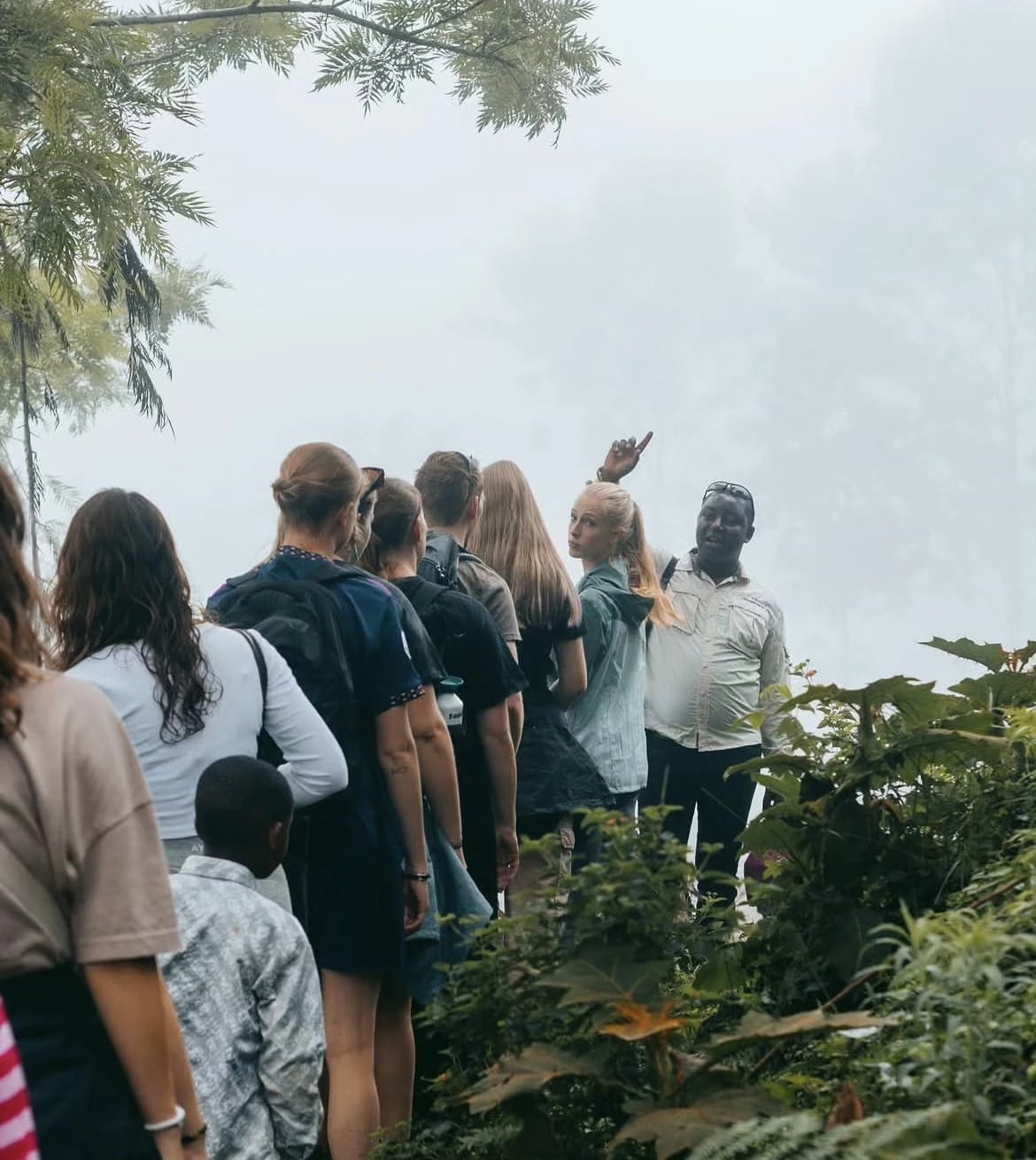 A guide speaking to a group on a path beside a waterfall